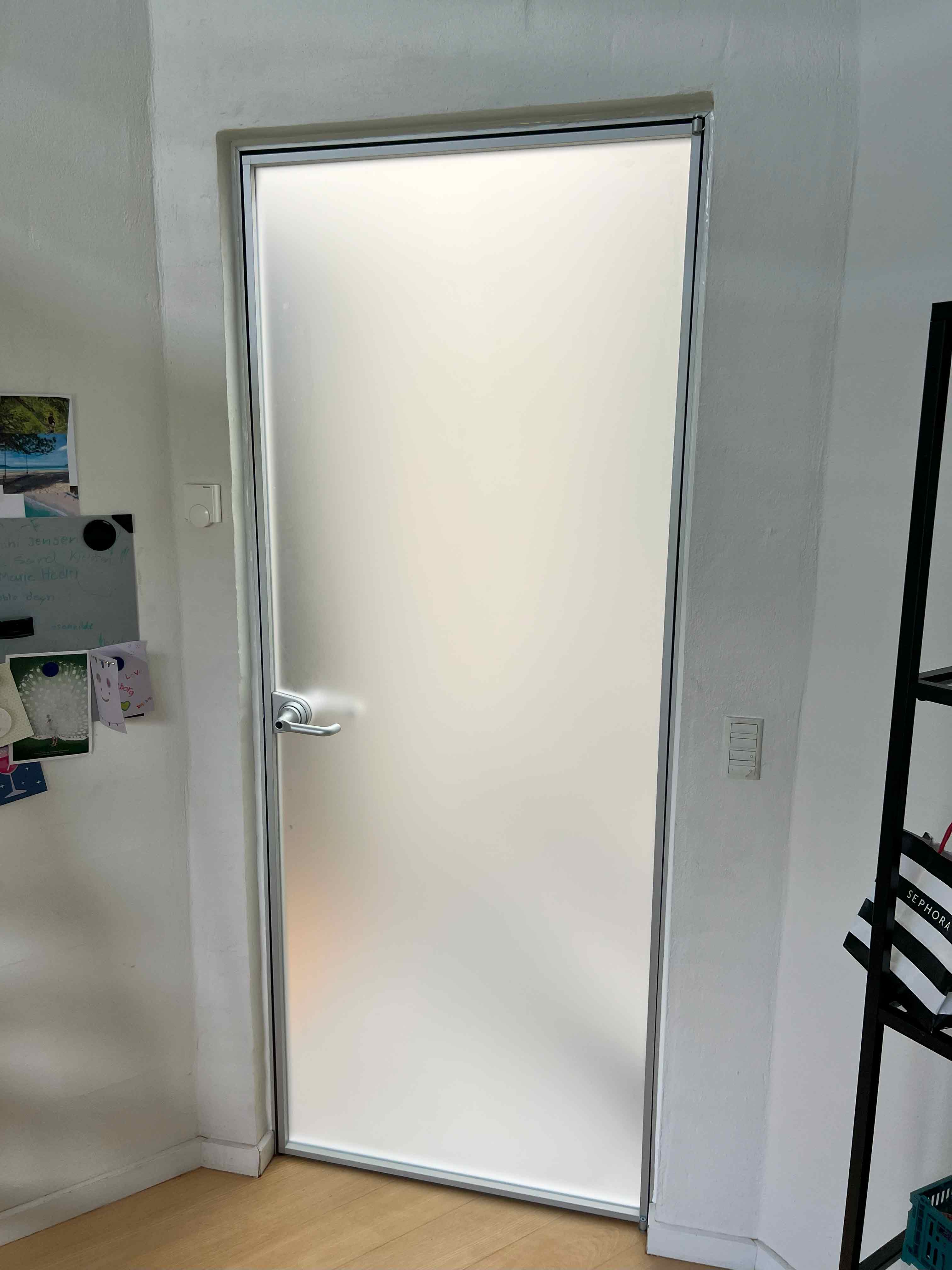 Højkvalitets interiørdør med elegant aluminiumsramme og sandblæst glas, designet af MogaByG til moderne indretning.