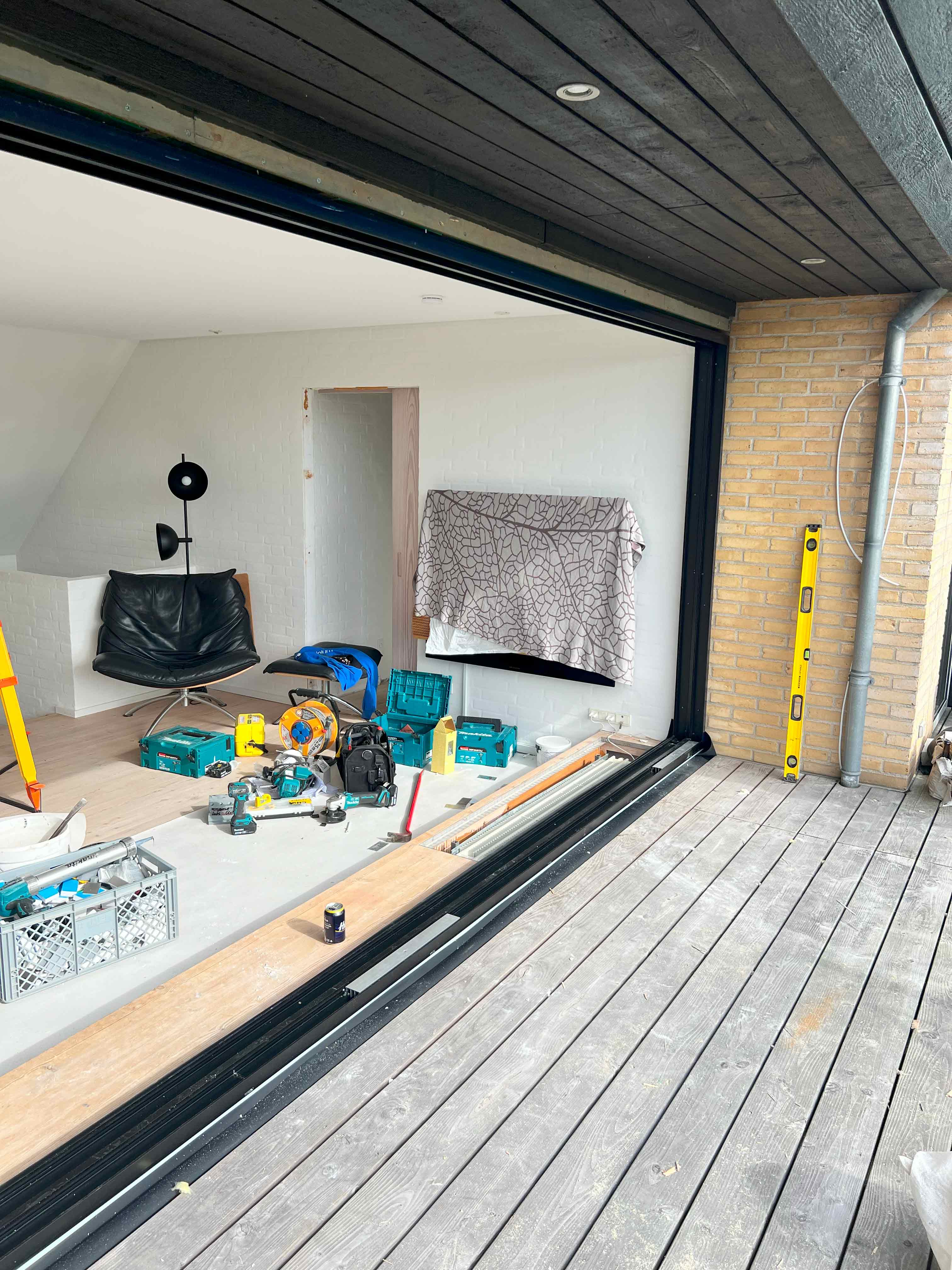 Installation af ny skydedør med stilfuld sort ramme, klar til at blive monteret med store glaspartier af MogaByG.