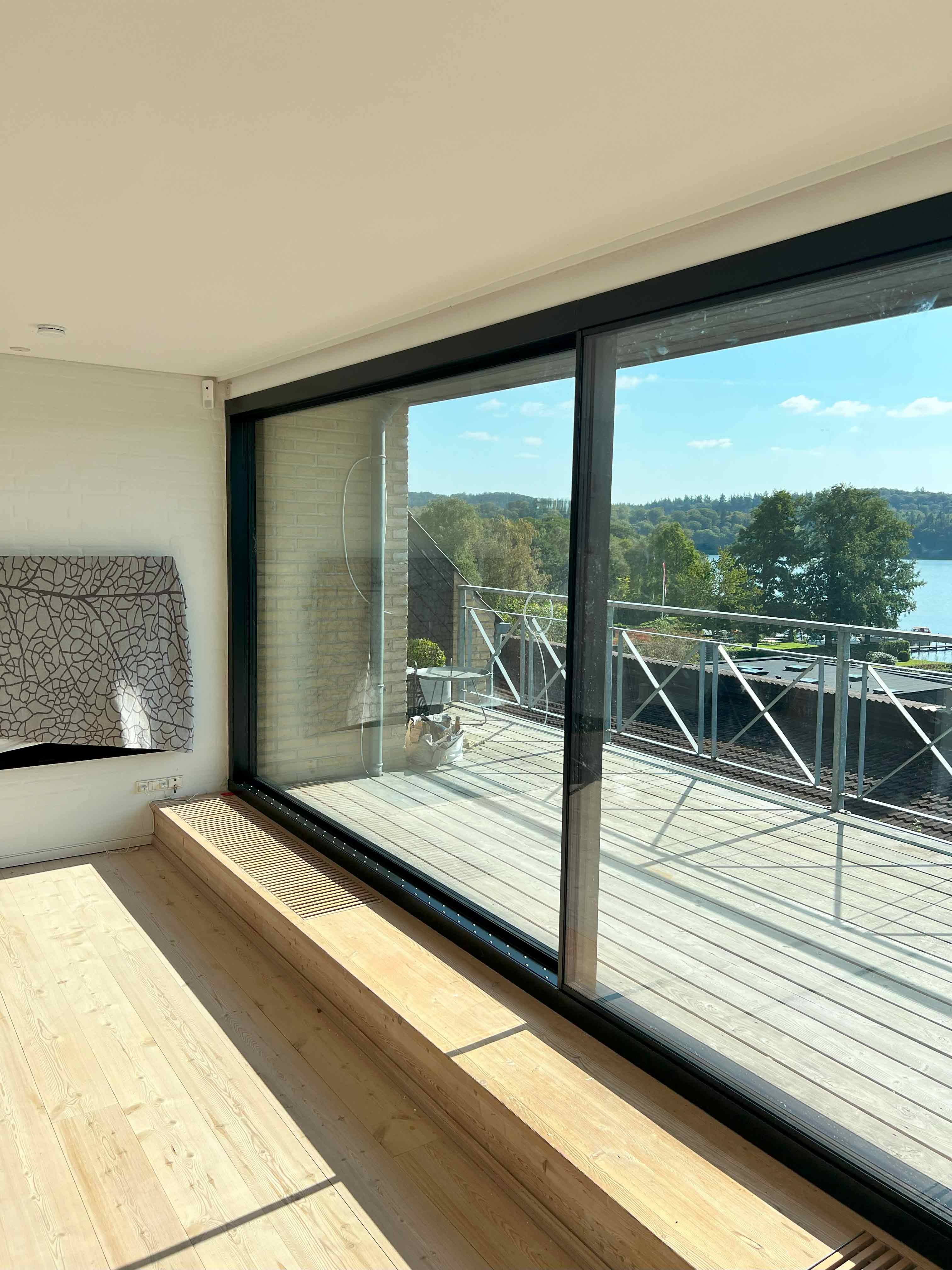 Færdiginstalleret skydedør med stor glasflade og sort ramme, lavet af MogaByG for et åbent og elegant udtryk.