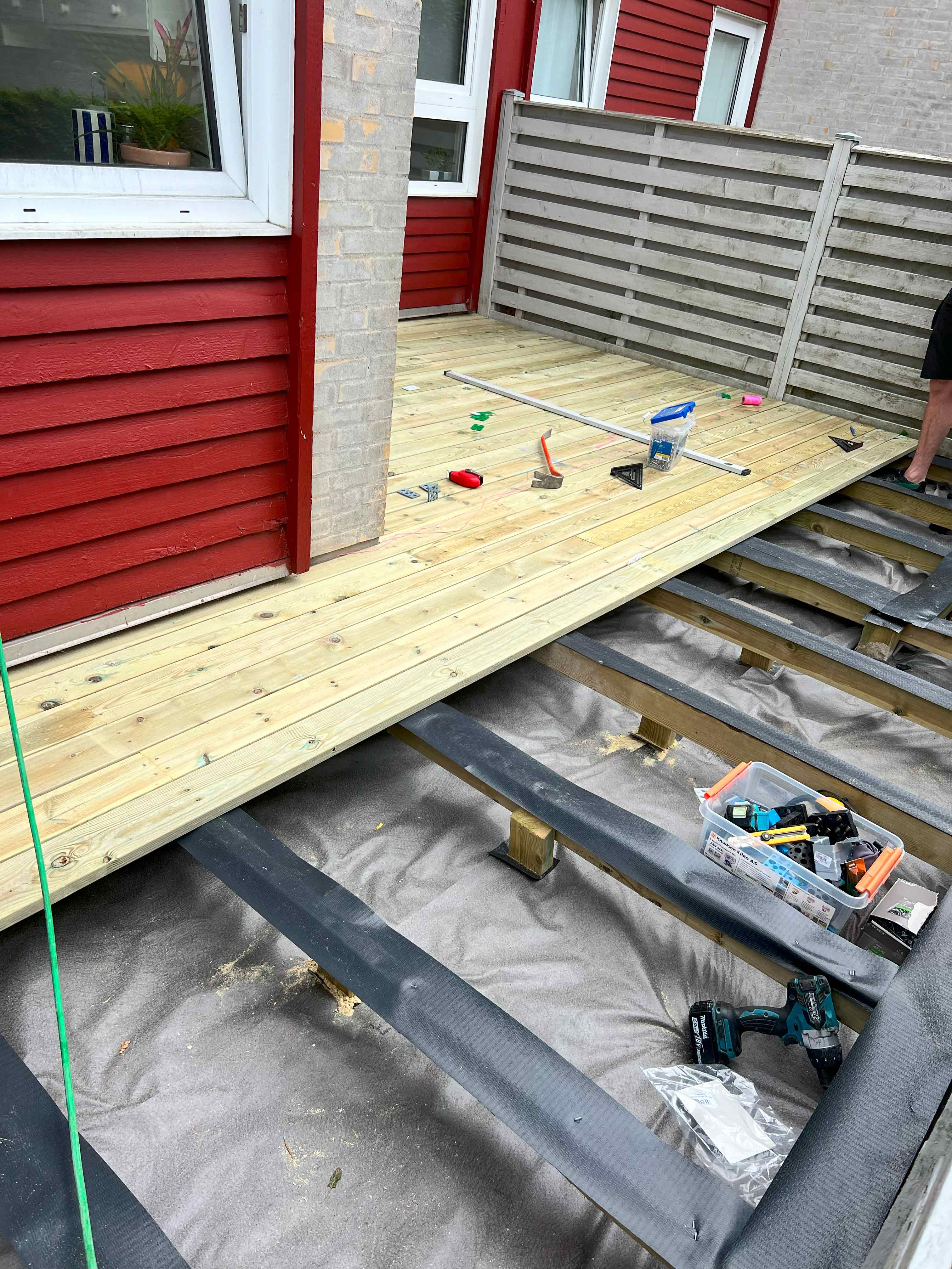 MogaByG færdiggør terrassekonstruktionen ved at tilføje de sidste brædder og sikre stabilitet og kvalitet.